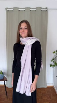 Écharpe violet clair en tissu doux, avec des bords à franges. Portée de manière décontractée sur un haut noir, retombant élégamment à l'avant.