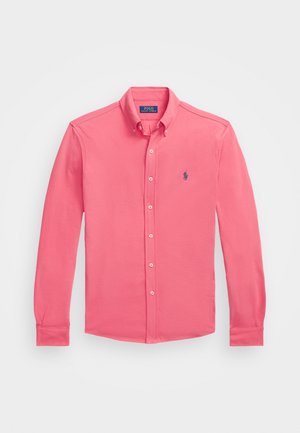 Camisa de botones en un brillante color rosa, de mangas largas, confeccionada en algodón, cuenta con un cuello clásico y un pequeño logo en azul marino en el lado izquierdo del pecho.