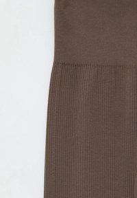 Brune ribbede stofleggings med en tætsiddende talje, der har en vertikal tekstur og en glat overflade. Ingen synlige metaldele eller bemærkelsesværdige detaljer.