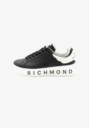Czarny niski sneaker z białą podeszwą, ozdobiony napisem "RICHMOND", czarnymi sznurowadłami oraz białym elementem w kształcie skrzydła na kołnierzu pięty.
