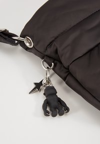 Czarna nylonowa torba z detalami w postaci srebrnego łańcucha, z breloczkiem w kształcie czarnej gorylicy oraz zawieszką w kształcie gwiazdy.
