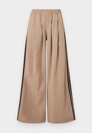 Bež široke hlače z elastičnim pasom in črnimi črtami na zunanji strani vsake noge.