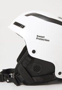 Biała narciarska kask z czarnymi akcentami, wyposażony w otwory wentylacyjne, regulowane paski i logo z napisem "Sweet Protection".