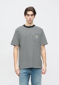 Ριγέ T-shirt σε λευκό και μαύρο, με στρογγυλή λαιμόκοψη και κοντά μανίκια. Περιλαμβάνει ένα μικρό λογότυπο στο στήθος.