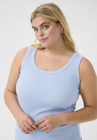 Helles blaues, geripptes Tanktop mit runder Ausschnittform und breiten Trägern. Das Model trägt einen Ring und hat lange blonde Haare.