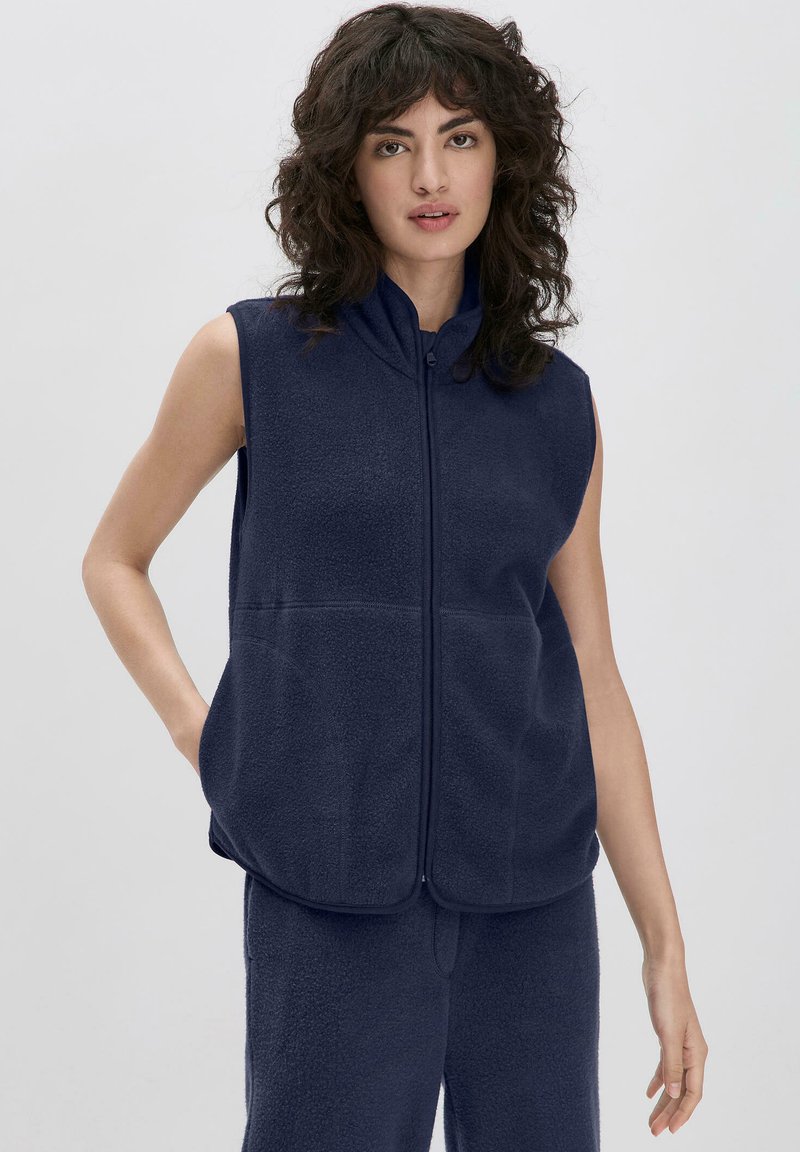 Navyblauer Fleece-Sleeveless-Vest mit hohem Kragen, vorderem Reißverschluss, zwei Seitentaschen und weichem Material, kombiniert mit passenden Hosen.