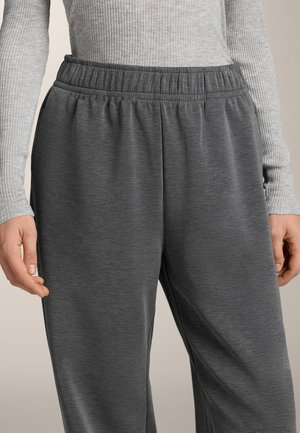 Pantaloni della tuta grigi con vita elasticizzata, caratterizzati da una texture liscia e una vestibilità comoda, abbinati a una maglia a maniche lunghe a costine di colore grigio chiaro.