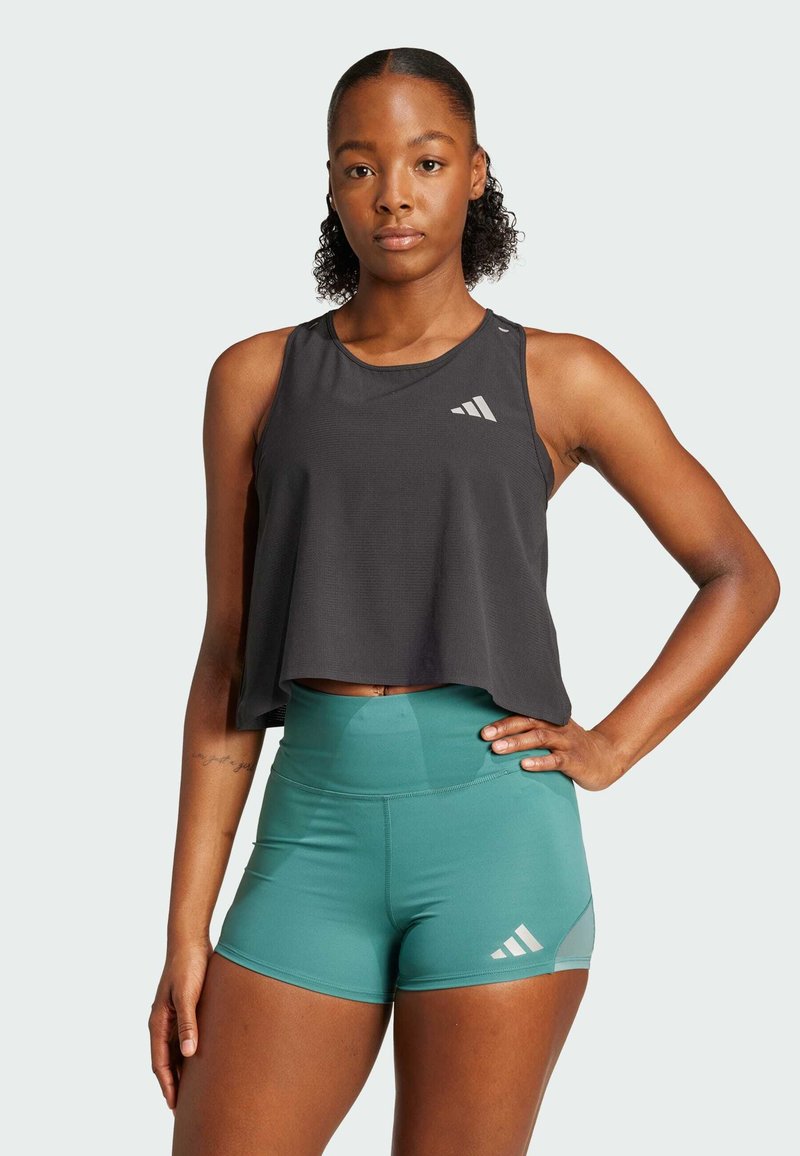 Ærmeløs sort crop top med et sporty design, parret med tealfarvede højttaljede shorts, der har tre hvide striber på siden.