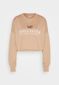 Zkrácená béžová mikina s dlouhými rukávy, na přední straně s bílým nápisem "HOLLISTER SOUTHERN CALIFORNIA" a emblémem. Měkký materiál.