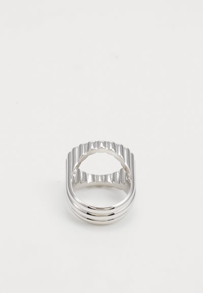 Silver ring featuring a wavy, ribbed design along the band, open back, and shiny smooth surface; minimalist aesthetic.