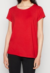 Rød kortærmet T-shirt med rund halsudskæring, lavet af blødt stof, med en afslappet pasform og glat tekstur. Sammen med sorte bukser.