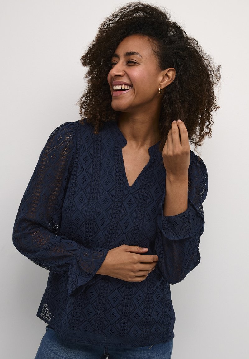 Blusa blu navy con un motivo testurizzato simile a pizzo, con scollatura a V e maniche svasate. Progettata per una vestibilità rilassata.