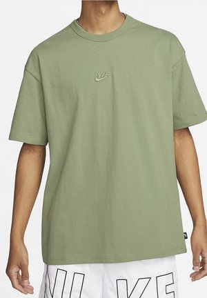 Olivegrünes Baumwoll-T-Shirt mit Rundhalsausschnitt, kurzen Ärmeln und einem tonal gestickten Nike-Logo auf der Brust. Glatte Textur.
