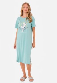 Vaaleansininen puuvillainen yöpaita, jossa on lyhyet hihat ja Snoopy-kuvitus. Sivuleikkaukset parantavat liikkuvuutta. Yhdistetty harmaiden liuku-sandaalien kanssa.