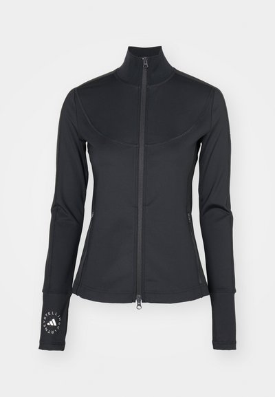Svart jakke med glidelås og høy krage, lange ermer og tommelhull. Glatt tekstur med kontrasterende sømmer og logo-detail på ermet.