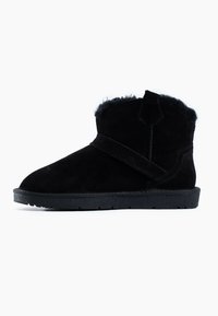 Botas de tobillo de ante negro con un suave forro de piel de pelo y una correa diagonal en la parte superior. Suela plana con textura para un buen agarre.