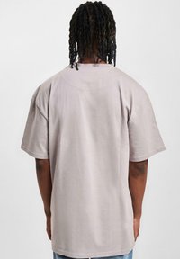 Light grey oversized t-shirt featuring a round neckline and short sleeves, made from soft fabric with a smooth texture.