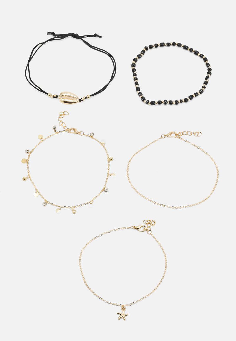 Cinq bracelets comprenant un cordon noir avec accent en coquillage, un bracelet en perles noires, et trois chaînes dorées avec des pendentifs et des disques variés.