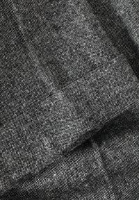Black and white textured fabric with a woven pattern, featuring a subtle speckled appearance and soft finish, folded in layers.