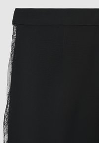 Schwarze Hose aus einem glatten Stoff mit einem Spitzenbesatz an der Seite. Der Bund ist flach und ohne Verzierungen gefertigt.
