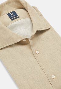 Camisa de lino beige con cuello puntiagudo, cierre de un botón y una textura sutil. La etiqueta dice "Boggi Milano, Corte Regular."