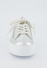 Sneaker metallico argento con design perforato, lacci crema e suola a piattaforma bianca. Presenta linee eleganti e una texture liscia.