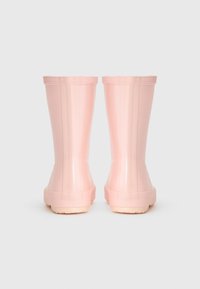 Bottes de pluie en caoutchouc rose avec une finition brillante, hauteur mi-mollet, et semelle texturée pour une meilleure adhérence. Design sans couture avec un bord supérieur arrondi.