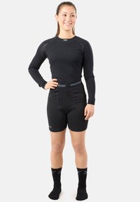Black long-sleeve shirt with ribbed texture, paired with black fitted shorts and socks. Label visible on the waistband, functional design.