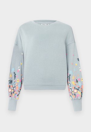 Lyseblå sweatshirt med blomsterbroderi i pink, gul og blå på ærmerne. Ribbet manchetter og halsudskæring, afslappet pasform.