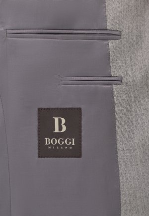 Šedá tkanina s vzorem herringbone má dvě paralelní kapsy vlevo. Na ní je vyšitá černá nálepka s nápisem "BOGGI MILANO" v bílé barvě.