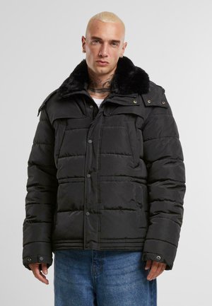 Sort puffer-jakke med en faux fur-krave, der har knaplukninger, sidelommer og et quiltet design for isolering.