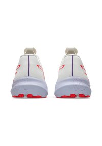White athletic shoes with a textured fabric upper, red accents, a purple stripe, and a speckled gray midsole. Rounded heel design.