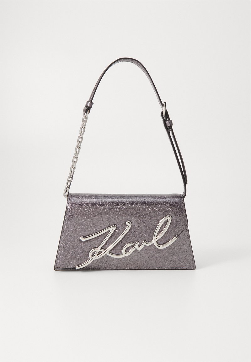 Metallinen harmaa käsilaukku, jossa on rakenteellinen trapezoidimuoto, hopeinen tunnetunnus ja yhdistelmäketju sekä nahkahihna.