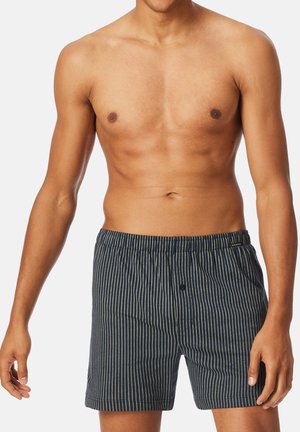 Boxer shorts da uomo a righe di colore blu scuro con linee verticali bianche, cintura elastica e dettaglio con bottone frontale. Tessuto morbido.
