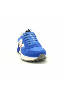 Blauer Sport-Schuh mit einer strukturierten Wildleder-Oberfläche, weißen und roten Markenlogos, einer gepolsterten Zunge und einer grauen Gummisohle mit Profilmustern.