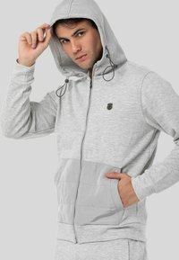 Grau aufgeknöpfter Kapuzenpullover aus Mischgewebe, mit strukturiertem unteren Bereich, Kordelzugkapuze und Fronttaschen. Kleines Logo auf der Brust.