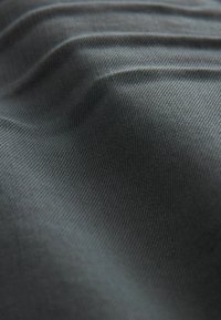 Țesătură de culoare gri închis cu o țesătură fină, prezentând pliuri delicate și un luciu subtil, indicând o suprafață moale și netedă.