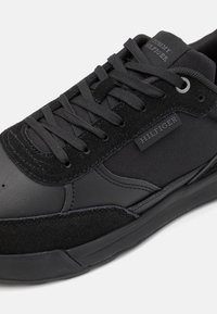 Sneakers neri caratterizzati da un mix di pelle liscia e suede testurizzato, con un pannello in rete, lacci piatti e un logo discreto.