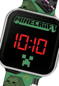 Orologio digitale con quadrante quadrato nero, display LED rosso che mostra le 10:10, e un cinturino verde con grafica e motivi a tema Minecraft.