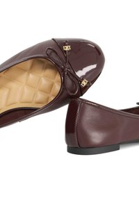 Burgundy patent leather ballet flats with a round toe, bow detail, and gold-tone accents. Textured insole and flat heel for comfort.