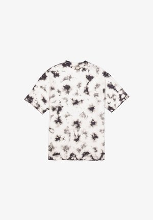Camiseta de algodón blanca con patrón de teñido anudado en negro. Manga corta, cuello redondo y corte holgado. Sin etiquetas visibles ni detalles metálicos.