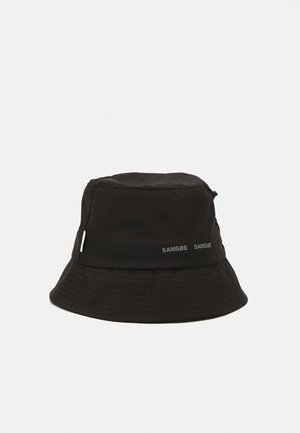 Cappello a secchiello nero realizzato in tessuto leggero, con corona rotonda e visiera ampia. Nome del marchio "SAMSØE" stampato in bianco sul lato.