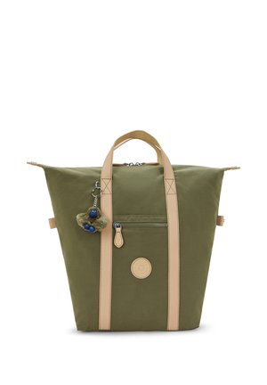 Olijfgroene canvas tas met beige handvatten, een ritssluiting aan de voorkant, een ronde logopatch en een klein pluche sleutelhanger bevestigd aan een van de handvatten.