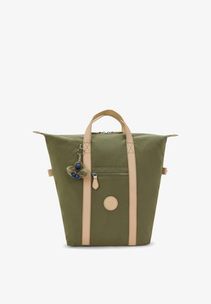 Olijfgroene canvas tas met beige handvatten, een ritssluiting aan de voorkant, een ronde logopatch en een klein pluche sleutelhanger bevestigd aan een van de handvatten.