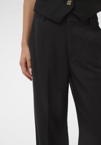 Black tailored trousers in a smooth fabric with a straight leg design, featuring front pockets and subtle crease lines for a polished look.