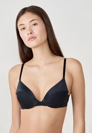 Reggiseno nero con ferretti, caratterizzato da coppe lisce e imbottite con un design a scollo profondo. Spalline sottili e regolabili e una finitura senza cuciture.