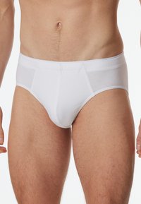 Weiße Baumwollunterwäsche mit breitem elastischem Bund, figurbetontem Design und flachen Nähten. Glatte Textur; keine sichtbaren Muster oder Beschläge.