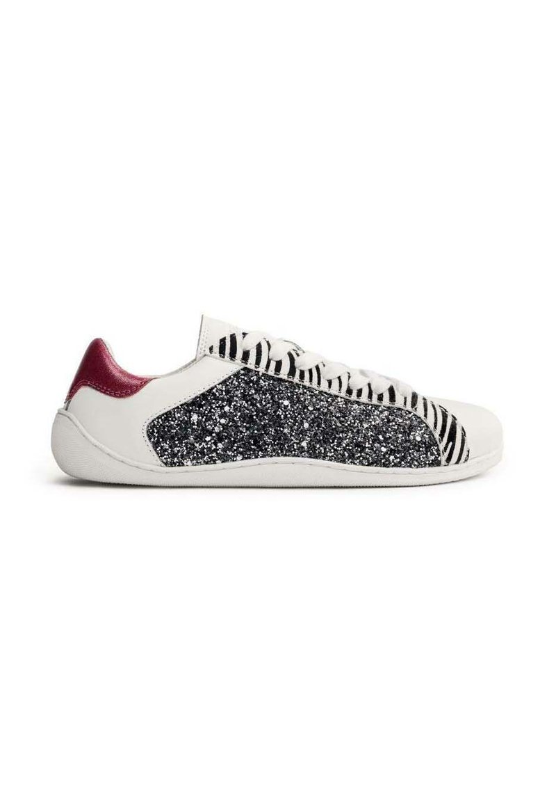 Zapatilla blanca con un panel lateral brillante en negro y plata, cordones de rayas de cebra y un acento en burdeos en el talón. Material suave, diseño de perfil bajo.
