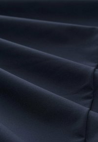 Tissu bleu marine avec une texture lisse, présentant des plis doux et un subtil éclat, indiquant un design léger et fluide.