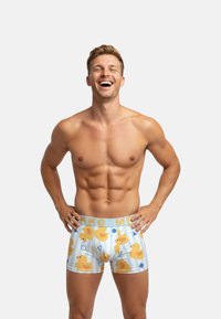 Kleurige herenboxers met een eendenprint op een lichtblauwe gestreepte achtergrond, voorzien van een zachte elastische tailleband met het label "MRKKO".